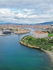 Aerial view of a coastal cityscape featuring a historic fort, modern buildings, and lush greenery along the waterfront, showcasing the beauty of urban architecture and nature