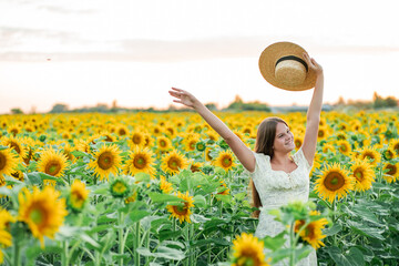 Smiling teenage girl in a hat having fun in a field of sunflowers. Enjoying life.