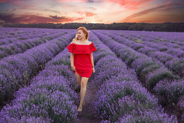 Girl in red clothes in purple lavender field at sunset in summer