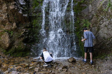 Two boys exploring a rocky waterfall at Kok Zhailau, Kazakhstan