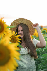 Smiling teenage girl in a hat having fun in a field of sunflowers. Enjoying life.