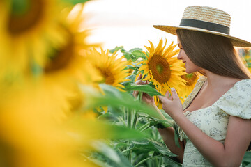 Smiling teenage girl in a hat having fun in a field of sunflowers. Enjoying life.