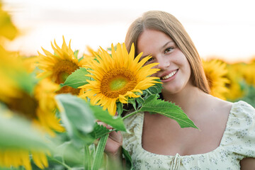 Closeup smiling teenage girl in a field of sunflowers. Enjoying life.