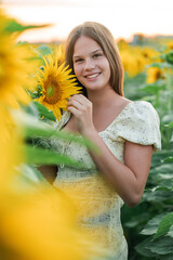 Smiling teenage girl in a field of sunflowers. Enjoying life.