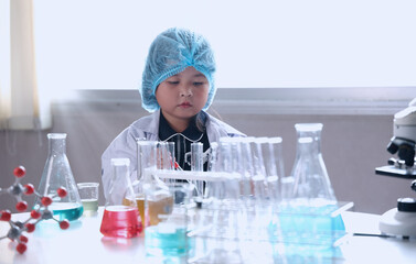 Kid and science. Child dress scientist learning conducts experiment in lab with colorful chemicals...