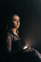 A mysterious woman stands in silhouette against a bright window, surrounded by dramatic smoke and...