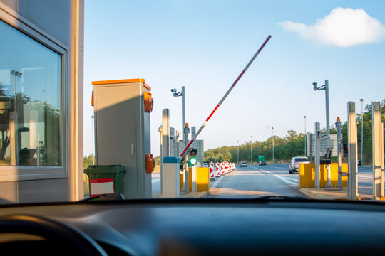  Car passing through checkpoint to pay highway toll. Man in car paying with card at toll booth to use highway or motorway.