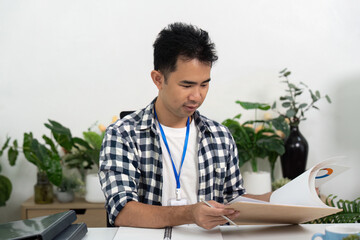 Organization. Young man reviewing documents while seated at a modern desk.