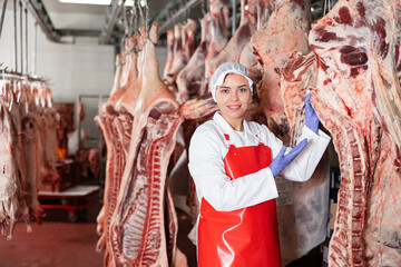 Female butcher in slaughterhouse showing piece of cow carcass