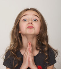 Oh please please please, may I please. Cute little girl pleading with hands clasped together, with...
