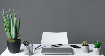Office table with laptop and chair on grey background, copy space. Modern office concept