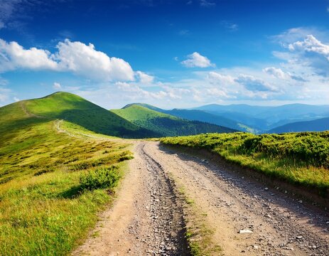 gravel country road in carpathian mountain scenic journey through alpine scenery of ukraine sunny day with clouds on the blue sky in summer - Powered by Adobe