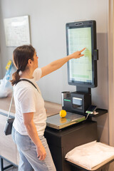 Woman weighing a lemon at a self-checkout. 