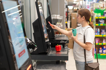 Woman paying with credit card at self-checkout. 