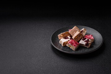 Nougat or white caramel with hazelnuts and pistachios and strawberry pieces. Nougat with nuts