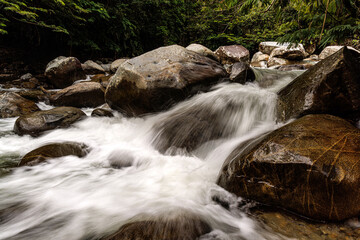Río de montaña con aguas blancas y rápidas fluyendo entre grandes rocas. Paisaje natural exuberante en San Rafael, Antioquia, Colombia. La fuerza del agua y la quietud de la piedra en un ecosistema vi