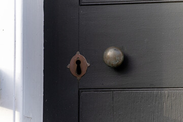 A black vintage wooden door painted with a matt finish. The exterior entrance of the white building...
