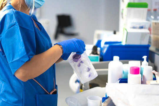 Nurse wearing mask and gloves is preparing medical equipment in a hospital room