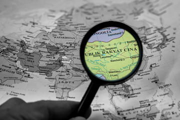 People's Republic of China on the world map, viewed through a magnifying glass, highlighting its...
