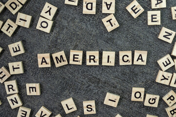 Wooden word block tiles spelling America are arranged on a top of black background table from a...