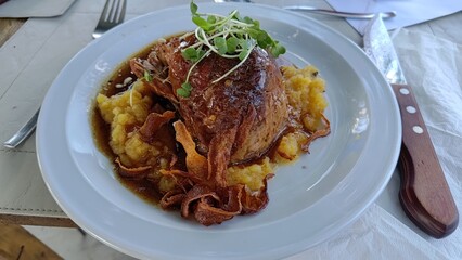Gourmet roasted pork dish served on creamy pumpkin puree with crispy onions and microgreens. A fine dining meal presented on a white plate in an elegant restaurant, ready to be eaten.
