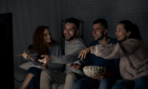 Let's watch this movie! Friends watching TV together, man trying to switch channels - Powered by Adobe