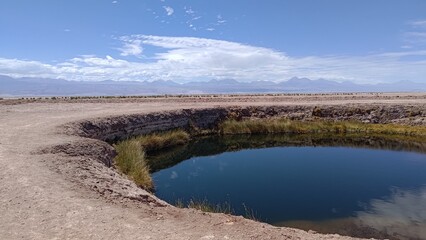 Panoramic view of Ojos del Salar, a natural oasis with a deep blue water lagoon in the middle of a...