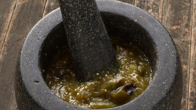 Homemade roasted tomatillo salsa with dried and toasted chilies de arbol in molcajete. Typical mexican dip. Rustic wooden table. 