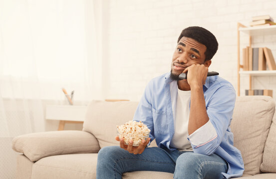 Nothing interesting on weekend. Boring african-american guy sitting at home with popcorn, expected fascinating film on tv, copy space