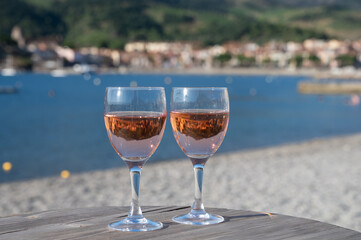 Glasses of rose Collioure AOC wine in sunlights with view on old town Collioure, colorful houses, church, castle and beaches, Occitanie, France, tourists destination