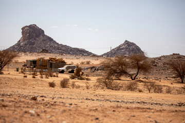 A humble desert hut built from bricks and topped with straw stands alone in the vast Algerian...