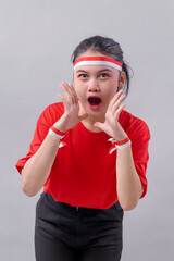 Confident Indonesian young woman enthusiastically shouting with both hands near her mouth, wearing...