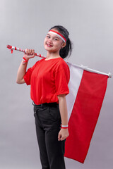 Smiling Indonesian girl in red shirt and black pants holds national flag on her shoulder with...
