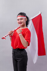 Young Indonesian woman smiling confidently while holding red and white flag across her shoulder and...