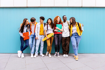 Young happy multiracial student friends standing over isolated blue background. Diverse teenage...