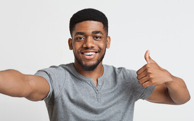 Fototapeta premium Blogger recommends. Happy african-american man making selfie and showing thumb up at camera