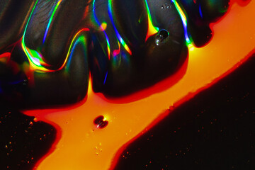 Vibrant Macro of Rainbow Light Over Dark Surface with Orange Liquid Flow