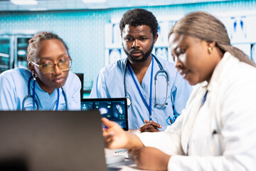 African american general practitioner leading a junior medical team in office, analyzing x ray...