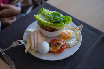 Delicious breakfast plate with fresh vegetables, eggs, and meats served at a cozy cafe in the morning sunlight
