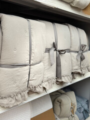 Folded Quilts with Floral Embroidery . Soft Pastel Textile Display on Shelf