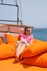 Relaxing on bright cushions by the ocean in sunny weather while enjoying a serene moment on a sailboat