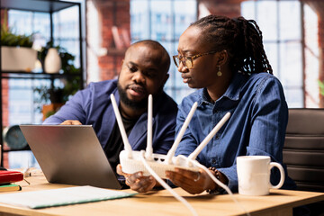 Young man and woman struggling with internet weak connection at home, pulling out LAN cable and adjusting Wi Fi settings to restore the signal. Freelancers couple with technical issues.