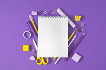 Back to school composition, open notebook, yellow and purple school supplies and stationery on...