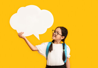 Asian Schoolgirl Holding Blank Speech Bubble Posing Over Yellow Studio Background. Mockup, Free...