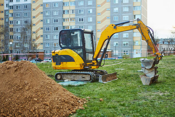 Crawler mini excavator with three buckets and bulldozer blade against the background of a mountain...