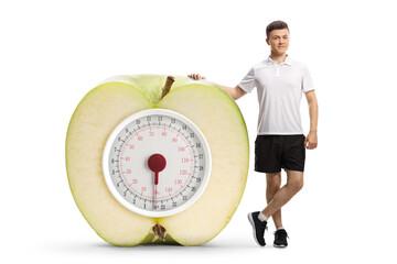 Full length portrait of a young man in sportswear leaning on a big apple scale