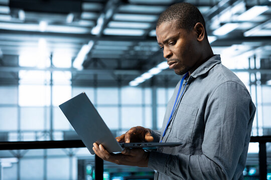 Technician in data center with laptop integrating AI driven automation tools, running predictive maintenance routines, analyzing operational metrics, ensuring continuous uptime, managing data flows