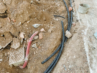 A chaotic and disorganized mess of tangled, jumbled wires is strewn haphazardly across the dirt,...