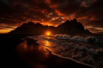 Sunset over mountains and ocean waves with dramatic orange clouds