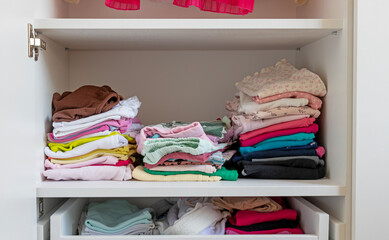 Folded children's clothes in the closet, storage of children's clothes.